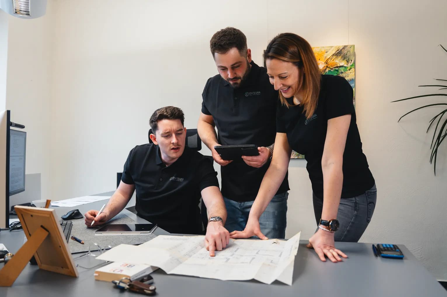 Team-Besprechung mit Bauplan und Tablet